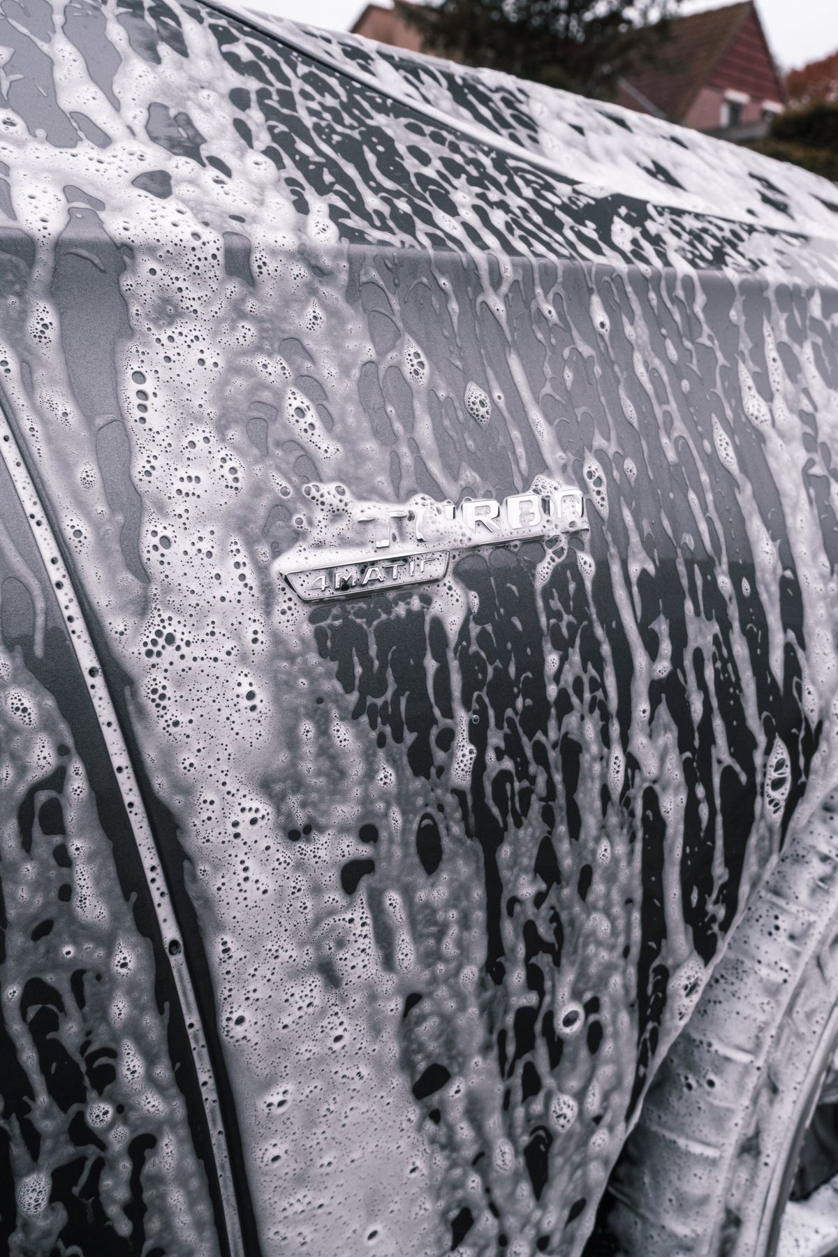 A car covered in wash suds during an exterior hand wash, for illustration